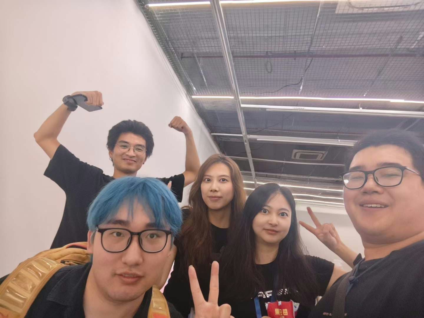 TRAE 大赛现场的五人合影，大家对着镜头微笑、比耶